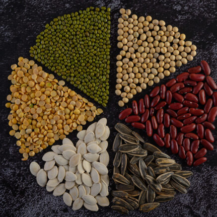 Legumes arranged in a circle on the black cement floor. Top view.